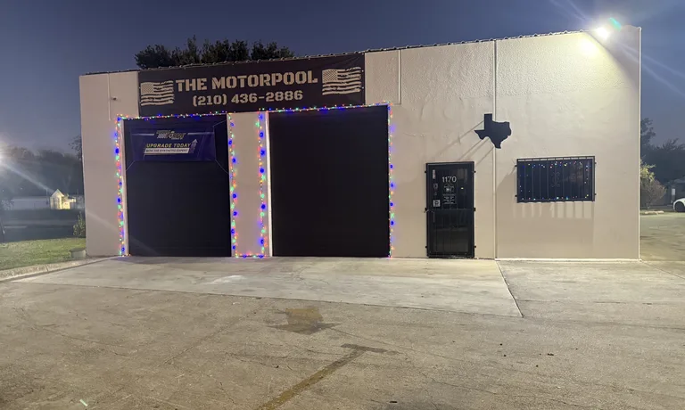 The Motorpool Quick Lube building at dusk: two service bays under The Motorpool sign with the shop phone number (210) 436-2886